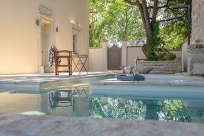 Ein Poolbereich mit Liege, Handtuch, einer Tür und einer Steinmauer mit Pflanzen.