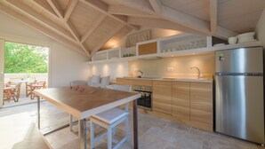 A modern kitchen with wooden beams, a stainless steel refrigerator, and a dining area with a wooden table and chairs. - Carpofoli Corfu (Corfu)