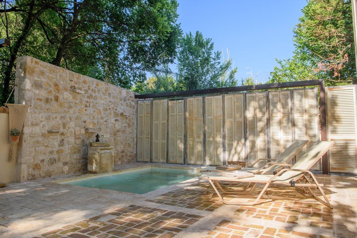 A stone-walled outdoor pool area with lounge chairs and a stone fountain.