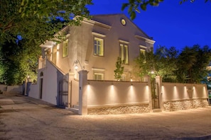 A two-story building with a stone wall, a gated entrance, and a staircase leading to the entrance.