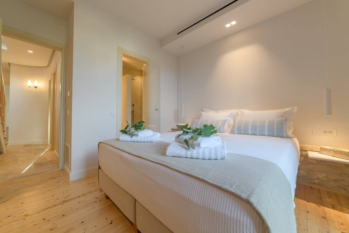A modern bedroom with a large bed, two bedside tables, and a wooden floor.