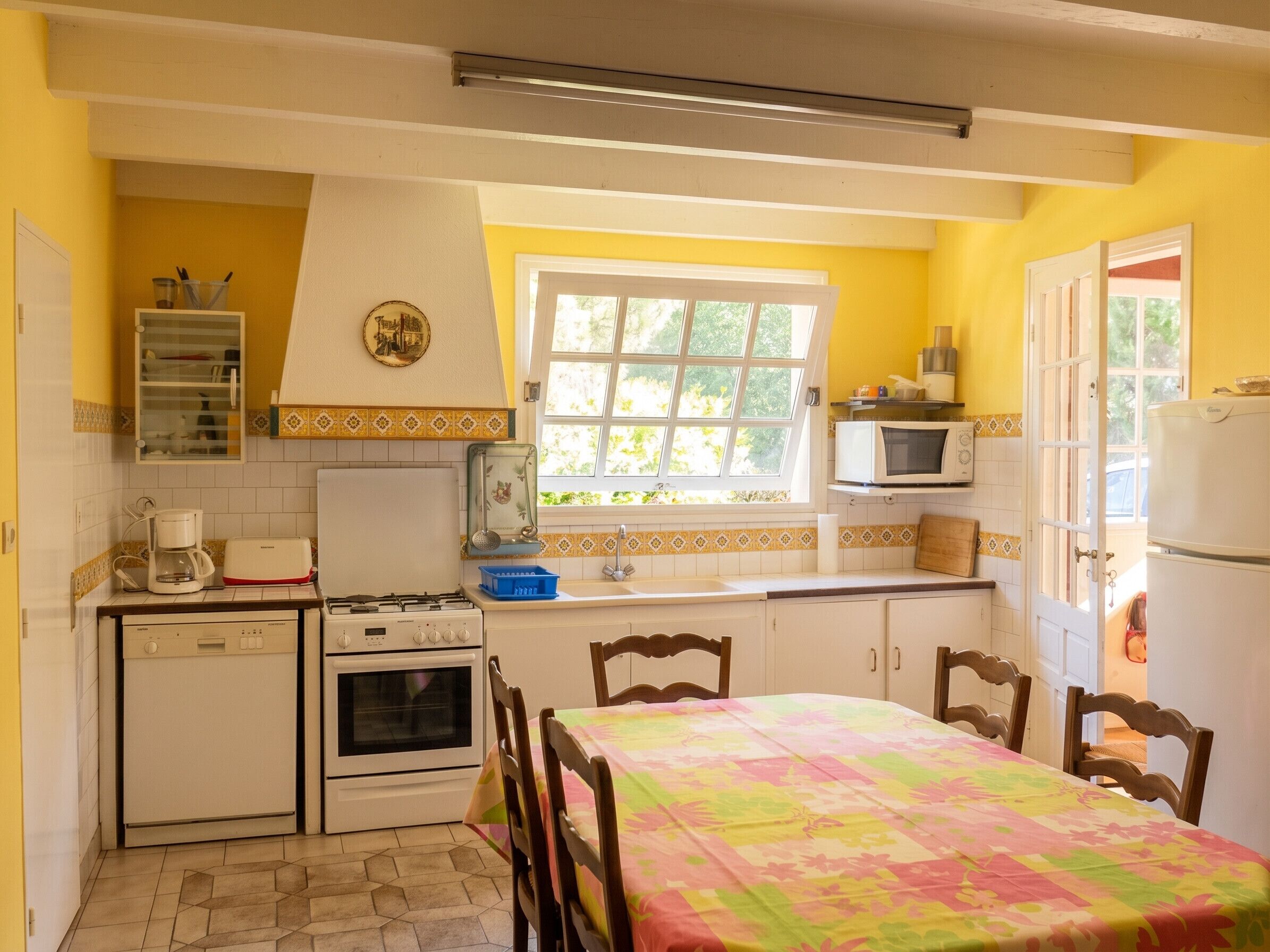 A compact kitchen with a dining area, featuring a stove, oven, microwave, and a window with a view.