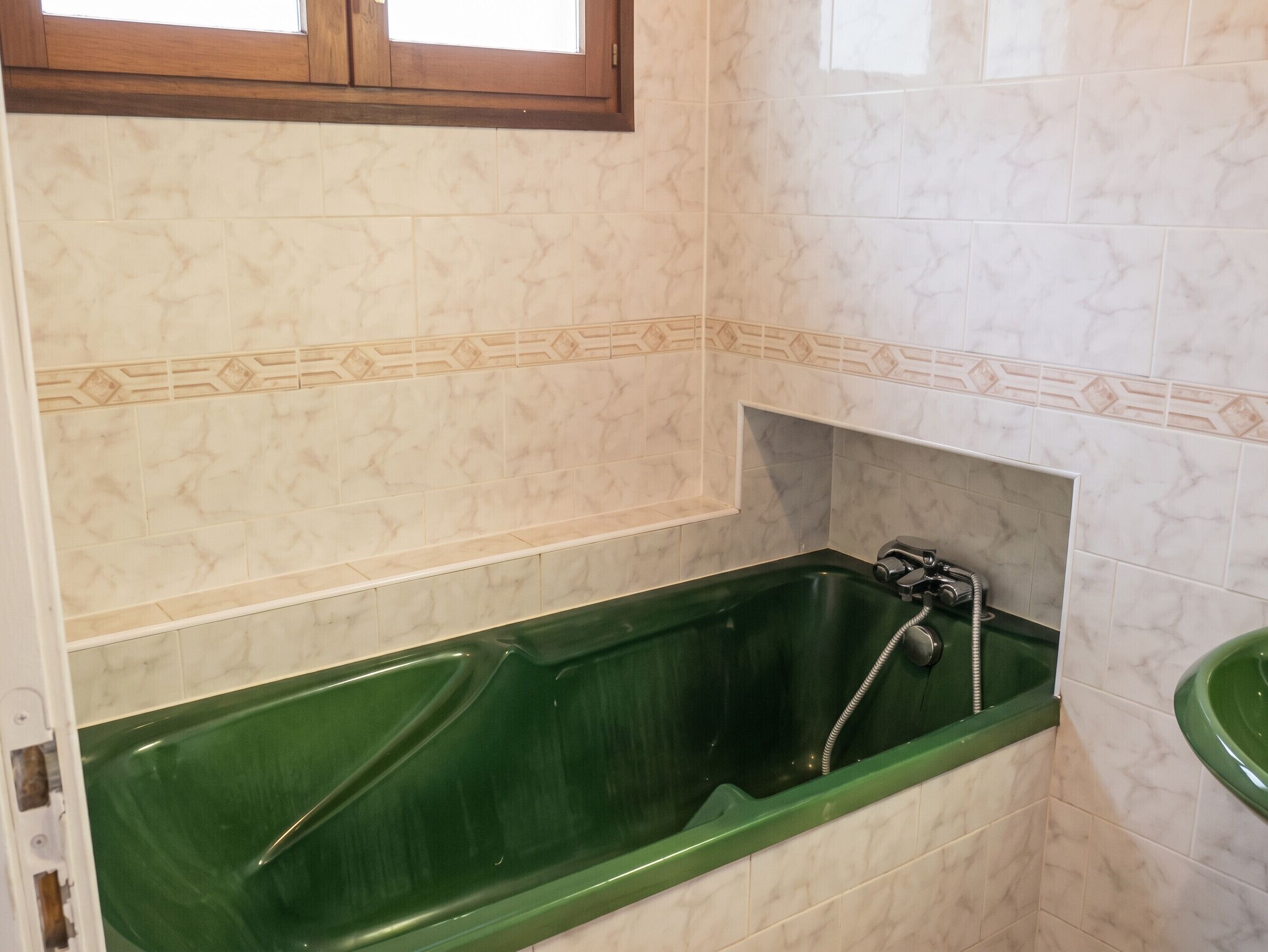 Een badkamer met een groen bad, een douche en een wastafel.