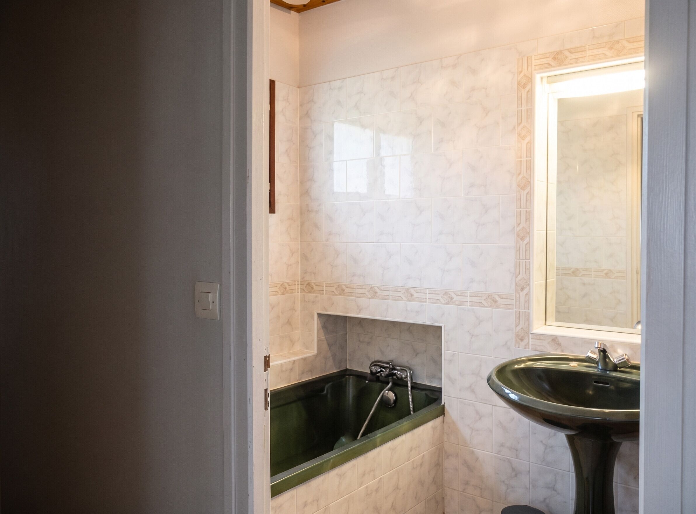 Une salle de bain avec une baignoire verte, un lavabo et un miroir.