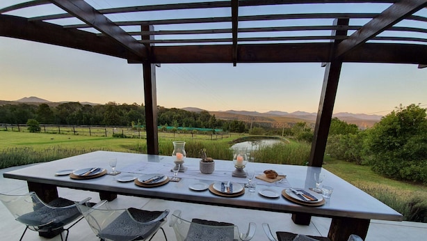 Une table à manger dressée pour quatre personnes, avec vue sur la campagne.