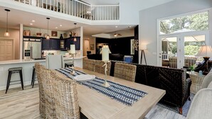 Un vaste espace de vie à aire ouverte comprenant une salle à manger, des meubles en osier et une vue sur l’extérieur.