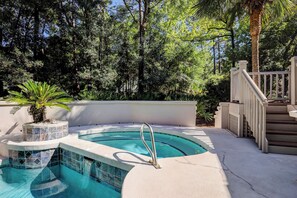 Ein Schwimmbecken mit Fliesenbord, eine Palme und eine Treppe zu einer Terrasse.