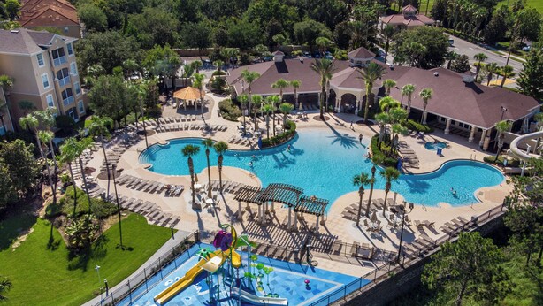 Luftaufnahme eines Resorts mit zwei Schwimmbecken, einem Wasserpark und umliegenden Palmen.