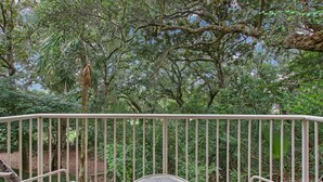 Un balcon avec des balustrades en métal, une table ronde et deux chaises.
