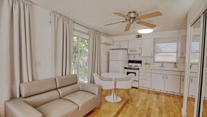 A compact living space with a sofa, a dining table, a ceiling fan, and a kitchenette. - GulfSide Resort has poolview on 2nd floor, onsite bbq, pool & putting green (St Pete Beach)