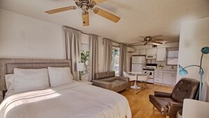 A bedroom with a large bed, a sofa, a chair, and a kitchenette in the background. - GulfSide Resort has poolview on 2nd floor, onsite bbq, pool & putting green (St Pete Beach)