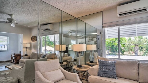 A modern living room with a sofa, armchairs, and a coffee table. There are two lamps, a mirror, and a ceiling fan. - Pool view.  Upstairs unit & workspace (St Pete Beach)