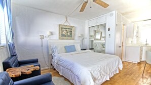 A bedroom with a bed, a ceiling fan, a dresser, and a window with curtains.