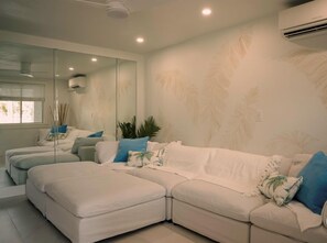 Une chambre d’hôtel moderne avec un grand lit, un canapé et un mur recouvert de miroirs.