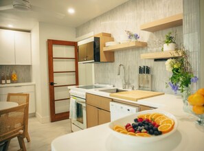 Une cuisine moderne avec des armoires blanches, un plan de travail en bois et un saladier rempli de fruits.