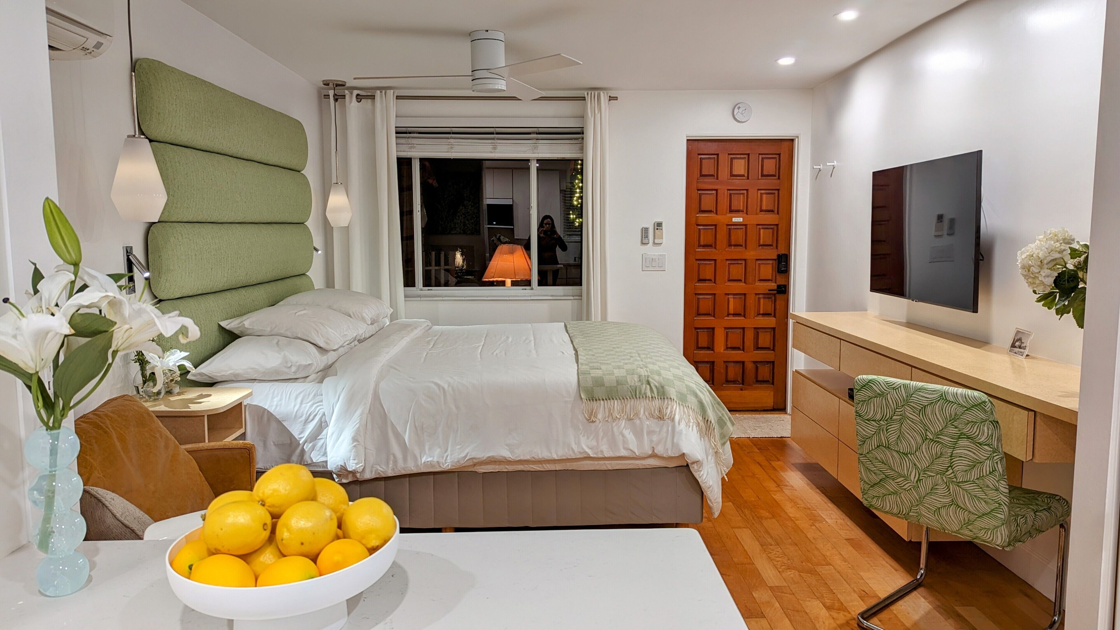 Une chambre moderne avec un lit, une table de chevet, une lampe et un bol de citrons.