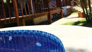 A poolside view of a building with a wooden deck and a tiled pool. - Planeta Banana B&B (Paraty)