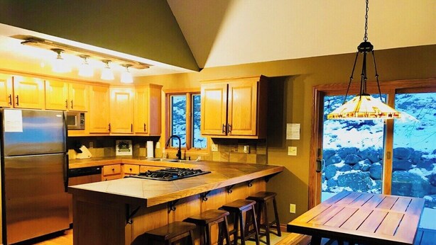 Una cocina moderna con armarios de madera, electrodomésticos de acero inoxidable y una isla grande con taburetes de bar.
