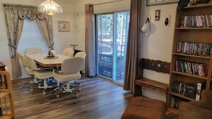 A room with a dining table, chairs, a bench, a bookshelf, and a sliding glass door leading to an outdoor area. - Beth`s Chalet in Pinetop (Pinetop)