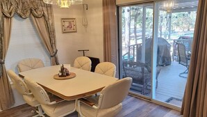 A dining area with a table and chairs, a picture on the wall, and a view through a glass door to an outdoor deck. - Beth`s Chalet in Pinetop (Pinetop)