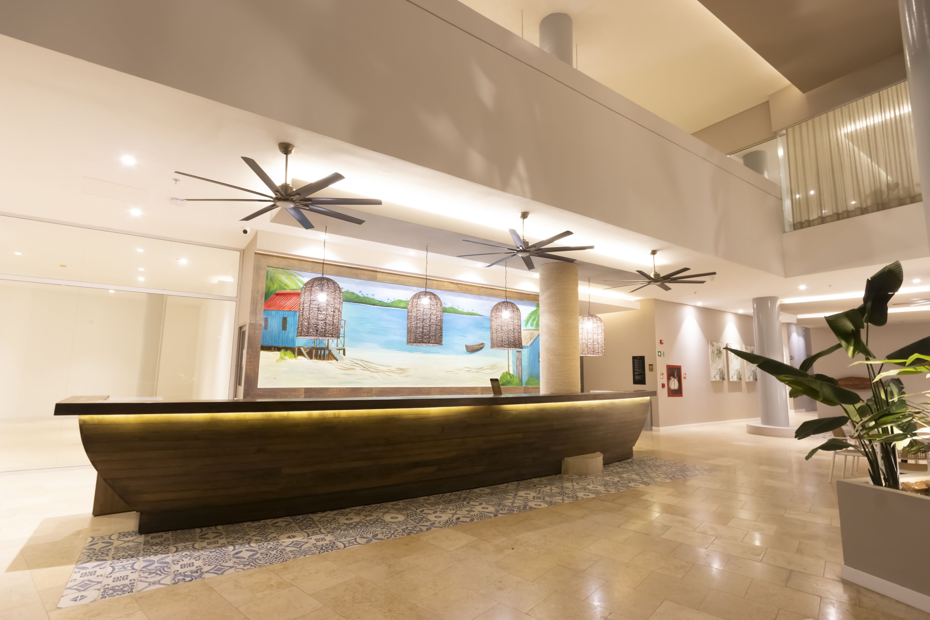 A reception area with a wooden reception desk, pendant lights, and a mural of a beach scene.