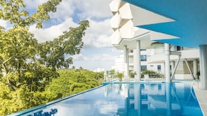 Un hôtel moderne doté d’une piscine, entouré d’une végétation luxuriante et offrant une vue sur un ciel dégagé.