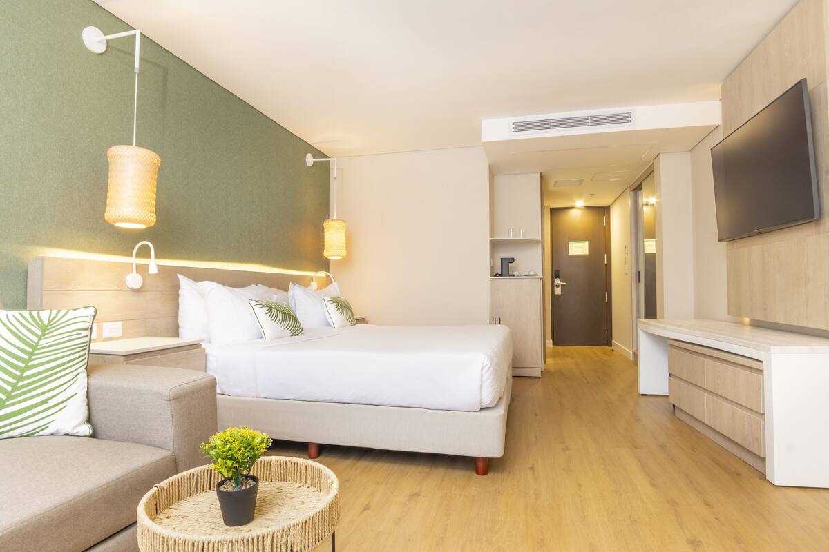 Une chambre d’hôtel moderne équipée d’un lit, d’un canapé, d’une télévision et d’une kitchenette.