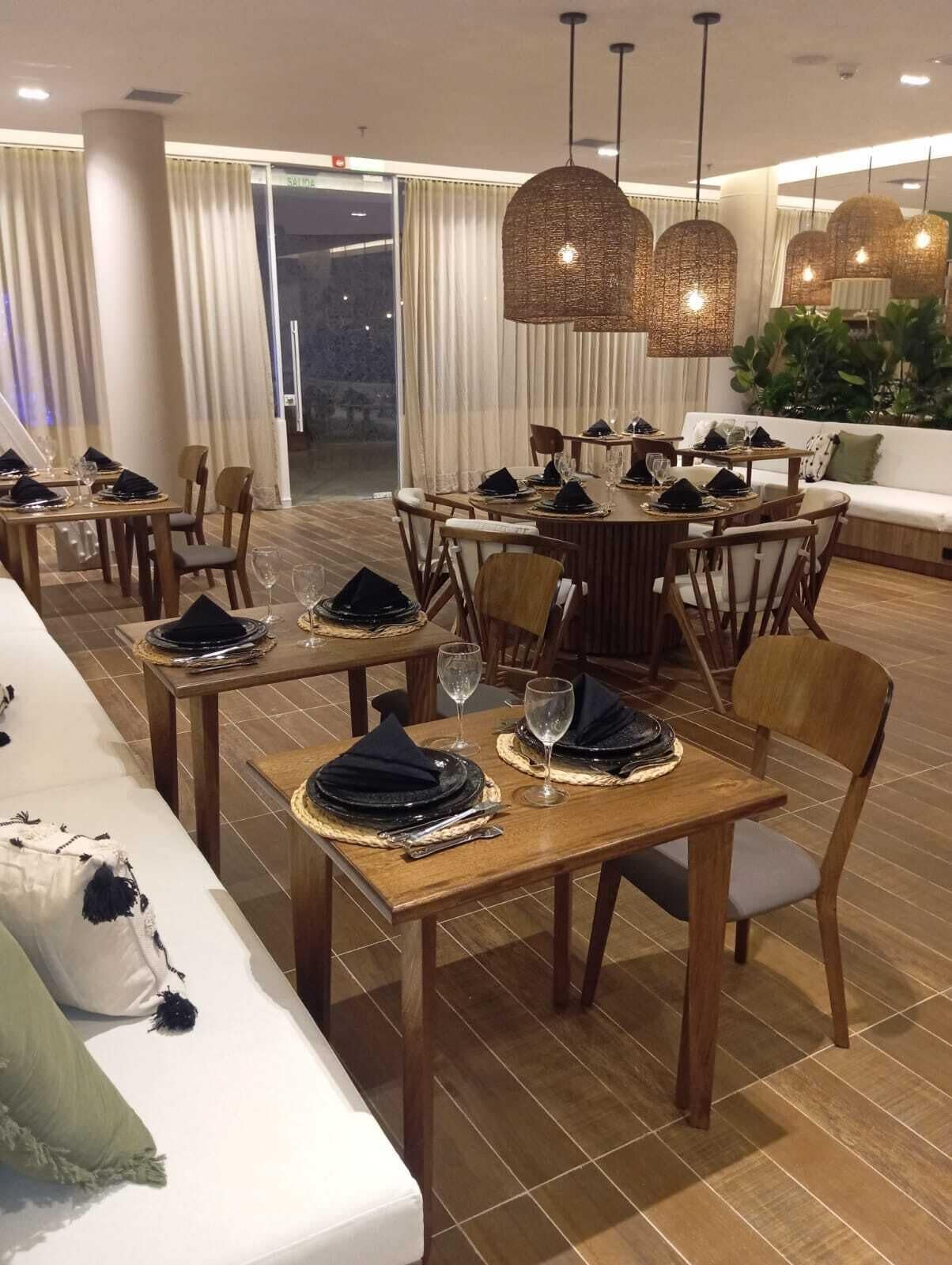A dining area with wooden tables set for a meal, surrounded by chairs.