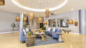 Un salon moderne avec un canapé bleu, des tables d’appoint en osier et des lampes suspendues en osier.