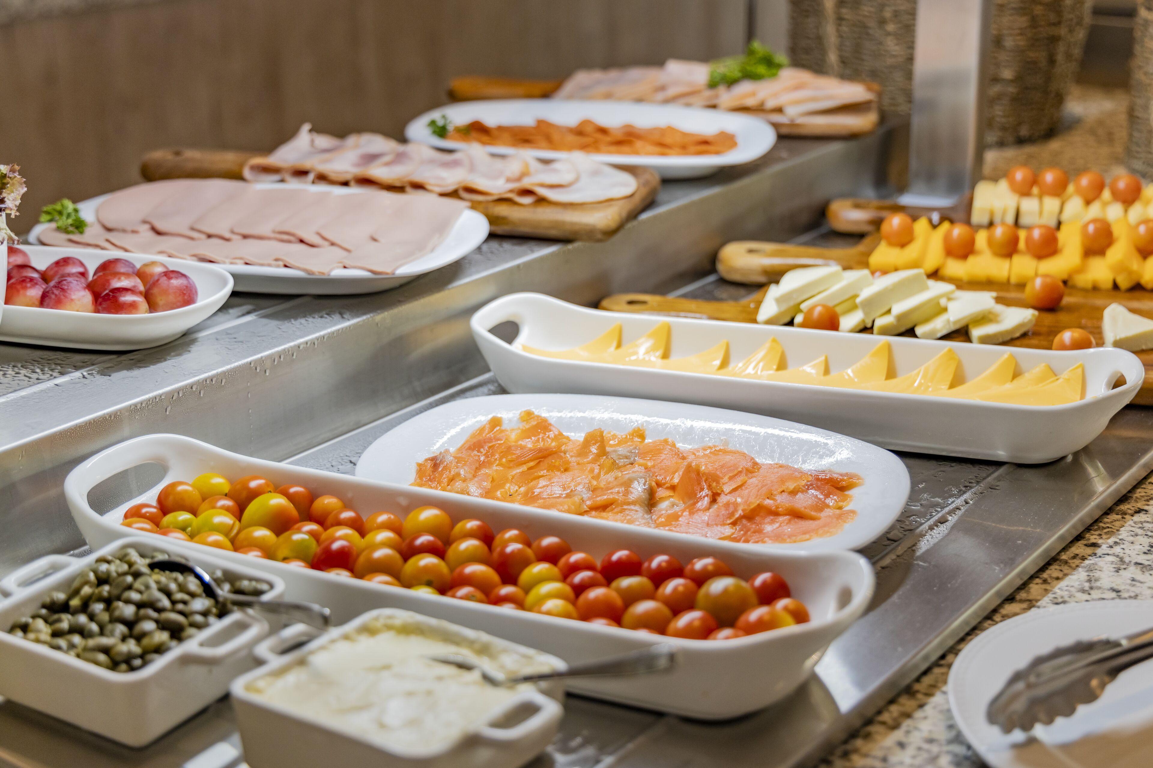 A buffet with various food items including meats, cheeses, and fruits.
