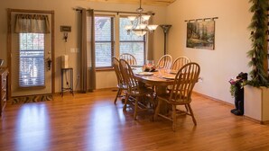 A dining area with a wooden table and chairs, a chandelier, and a painting on the wall.
