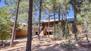 A log cabin with a wooden deck and stairs leading to a porch.