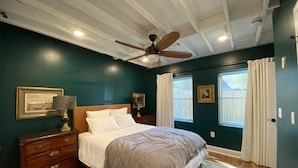 A bedroom with a bed, wooden dresser, ceiling fan, and two windows with curtains. - Monthly Rental Well Appointed Cottage in the Heart of WA near DT Chs & Beaches. (Charleston)