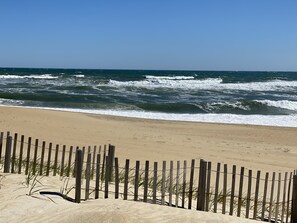 A sandy beach with a wooden fence and waves crashing onto the shore. - Oceanside Beach Cottage! Steps to the ocean!  Great Location!  Kitty Hawk, NC (Kitty Hawk)