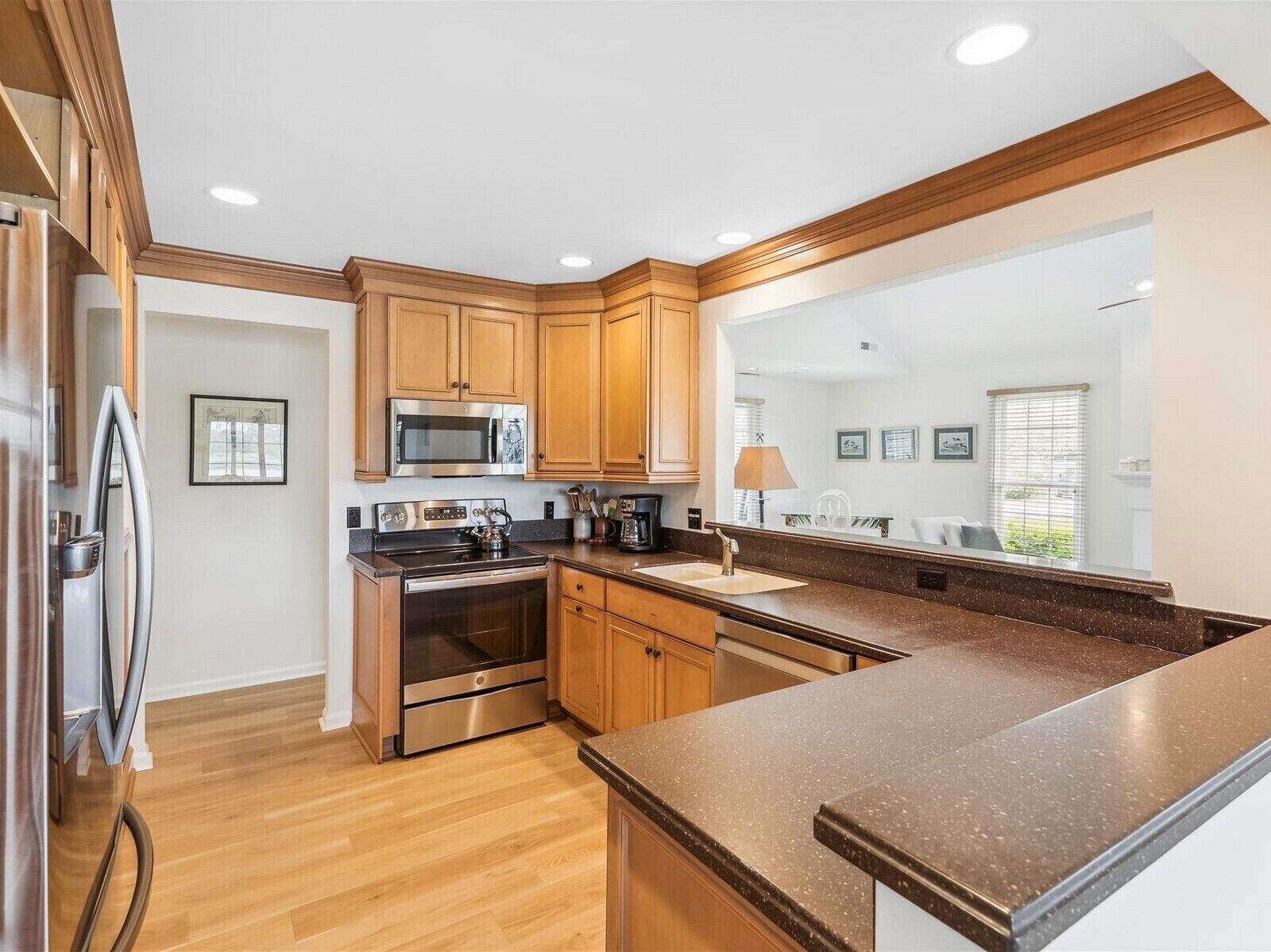 A modern kitchen with wooden cabinets, stainless steel appliances, and a granite countertop.