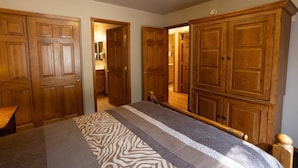 Un dormitorio con cama, armario de madera y espejo.