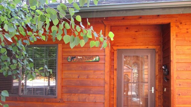 A wooden cabin with a sign reading 'Hands Haven,' a door with a glass panel, and a window with blinds. - Pinetop Country Club Hand Haven (Pinetop)
