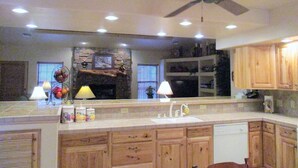 A kitchen with wooden cabinets, a central island with a sink, and a ceiling fan. - Pinetop Country Club Hand Haven (Pinetop)