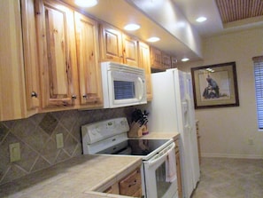 Une cuisine avec des meubles de rangement en bois, un four à micro-ondes, une cuisinière et un réfrigérateur.