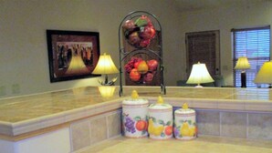 A kitchen with a fruit-themed spice rack, a framed picture on the wall, and two lamps on the countertop. - Pinetop Country Club Hand Haven (Pinetop)