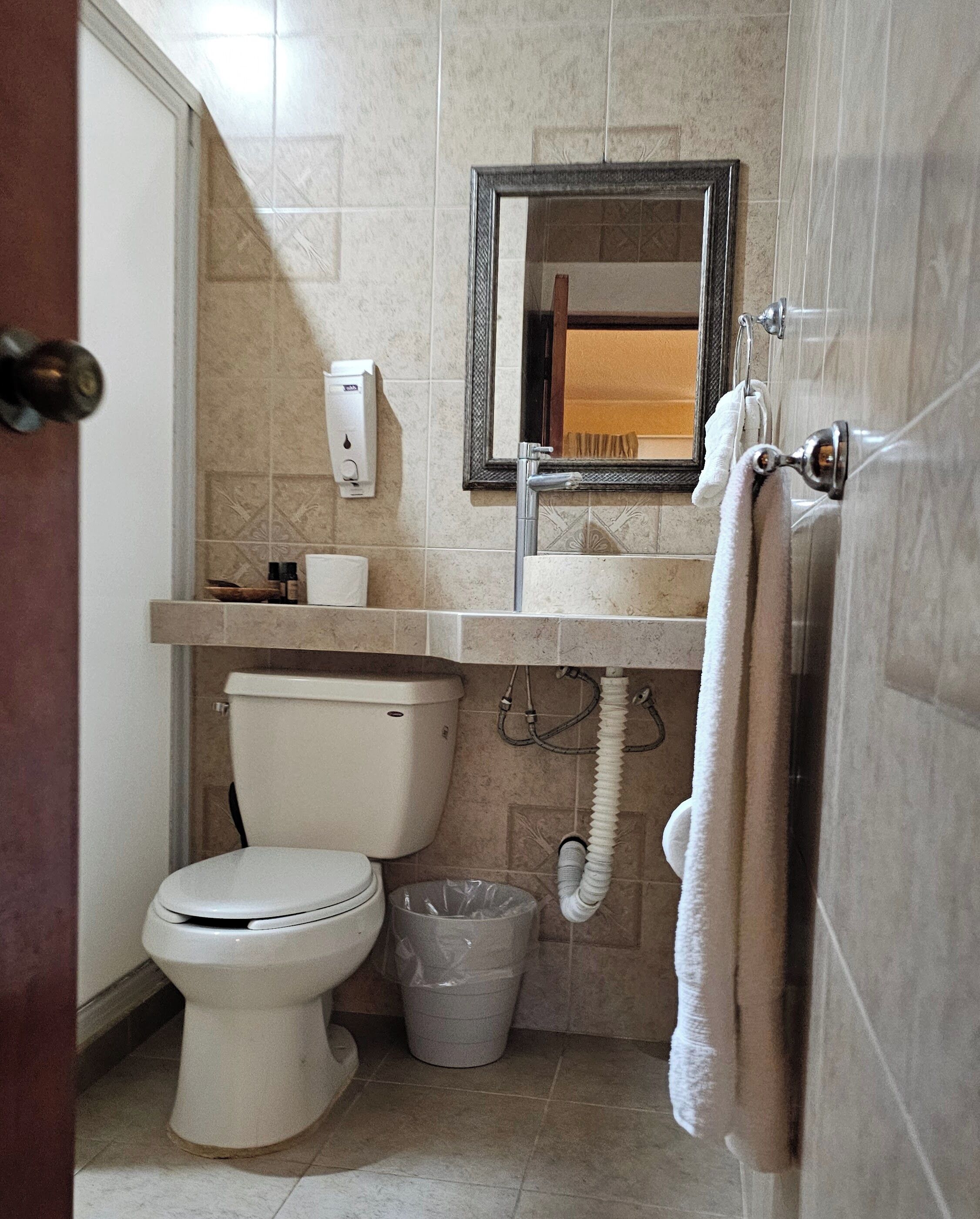 A bathroom with a toilet, sink, and mirror.