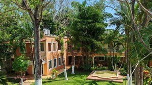 A courtyard with a pool, surrounded by trees and a building with multiple windows and balconies. - Hotel Los Cedros Uayamon (Uayamon)