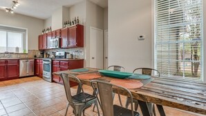 A kitchen with red cabinets, a wooden table, and a window with blinds. - Great Home in Austin's Wells Branch Neighborhood! (Austin)