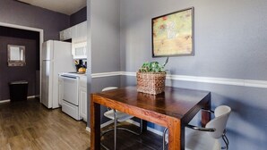Una cucina con elettrodomestici bianchi, un tavolo da pranzo in legno e un cesto con piante.