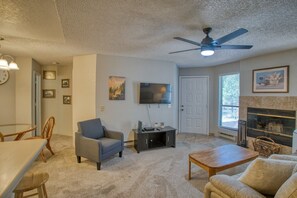 A living room with a ceiling fan, a flat-screen TV, a fireplace, and a dining area with chairs and a table.