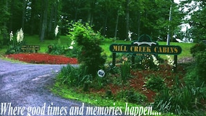 Señal de Mill Creek Cabins con un entorno natural y boscoso.