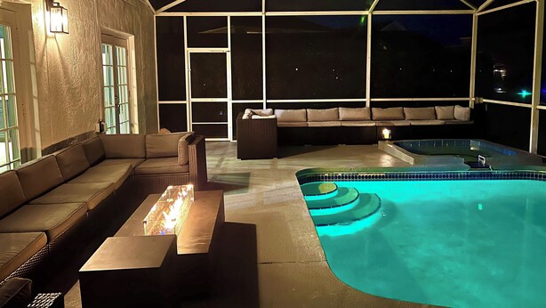 Et udendørs poolområde med jacuzzi, sofa og bord.