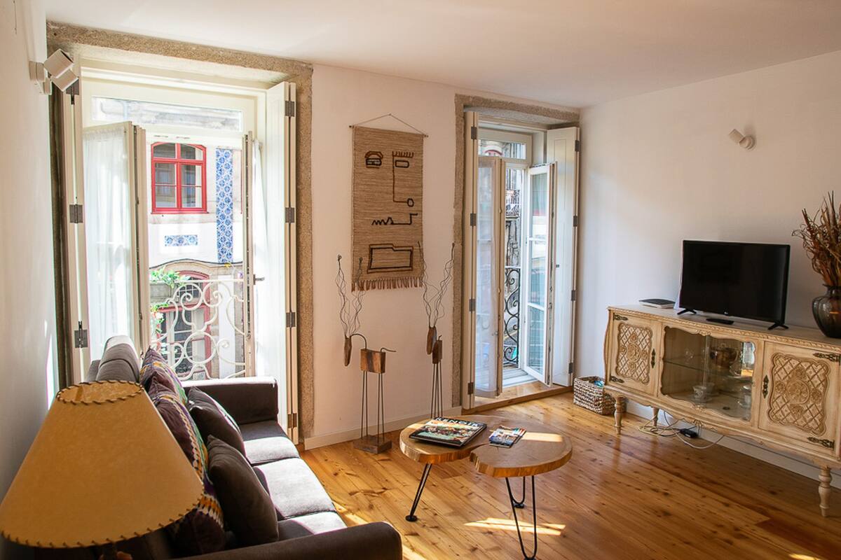 A living room with a sofa, a TV on a cabinet, and a door leading to an outdoor area.