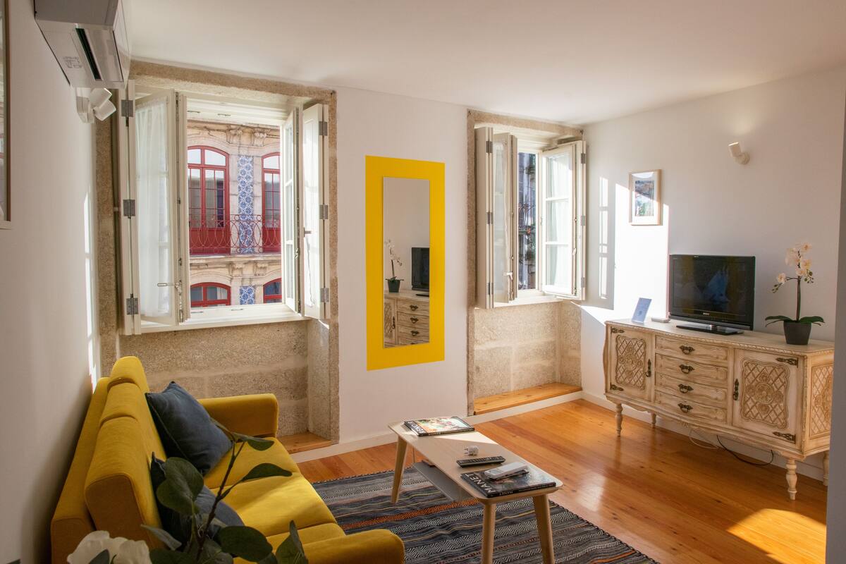 A living room with a yellow sofa, a coffee table, a TV, and a cabinet.