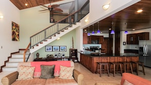 A spacious living area with a sofa, a coffee table, and a staircase leading to an upper floor. - Casa Antonelli (Sardinal)